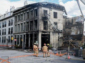 Firefighters stand next to a building in Old Montreal on Saturday, Oct., 5, 2024.