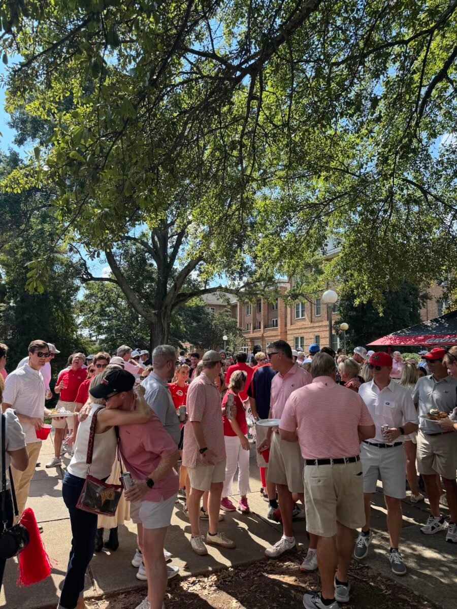 A large group of people dressed in red gather under trees