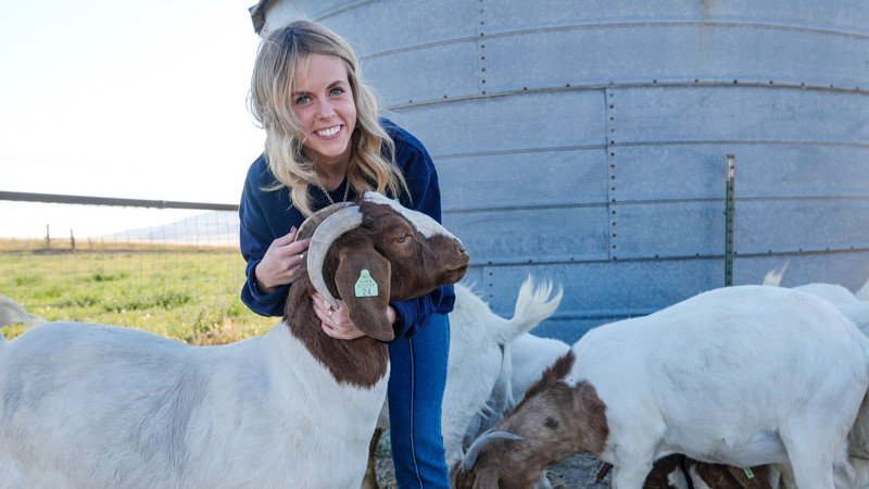 Brinley Rhodes in a field with her goats.