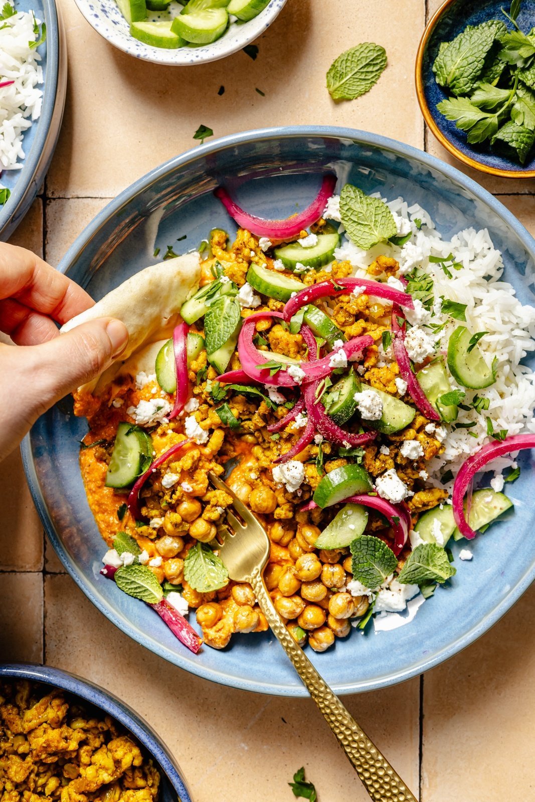 scooping a Mediterranean chicken bowl with pita bread